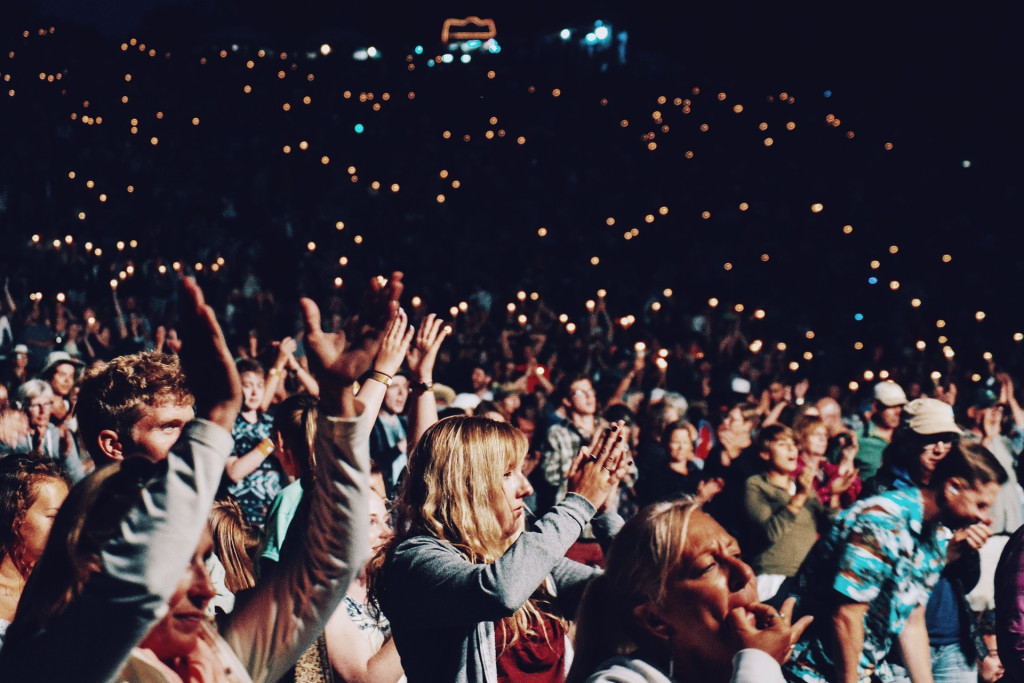 Large crowd of people attending a concert with their phones in the air.